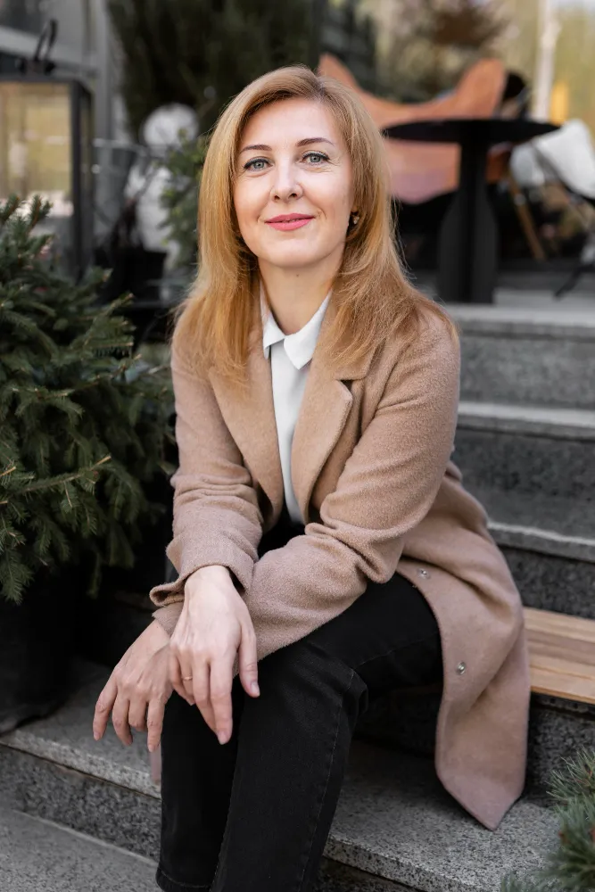 A woman in a brown coat sitting on steps.